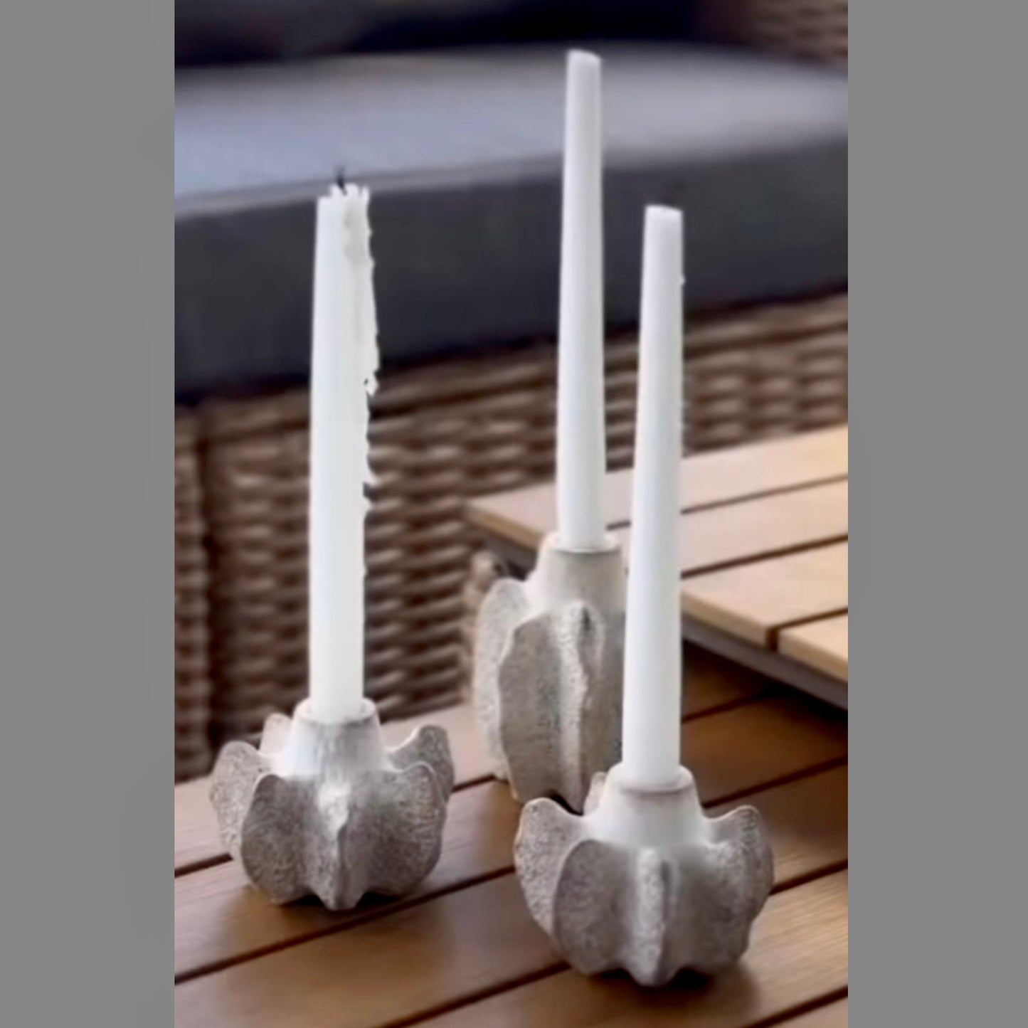 Two candle holders with white candles on a wooden surface
